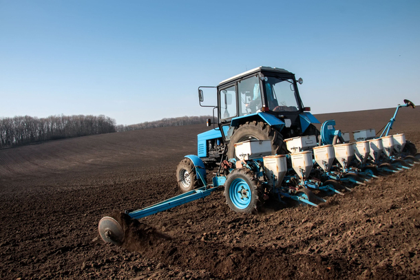 20198530 - blue tractor with sower on the field in bright sunny spring morning